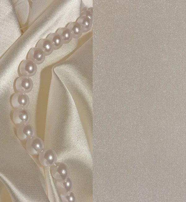 A strand of luminous pearls rests on draped satin fabric in a soft, neutral palette.