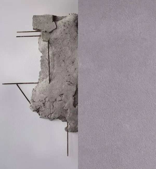 Rough concrete fragment with exposed rebar protrudes from a textured gray wall.
