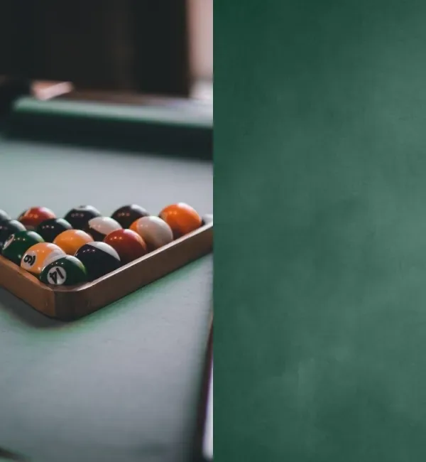 A rack of colorful billiard balls rests on a green felt pool table, ready for play.