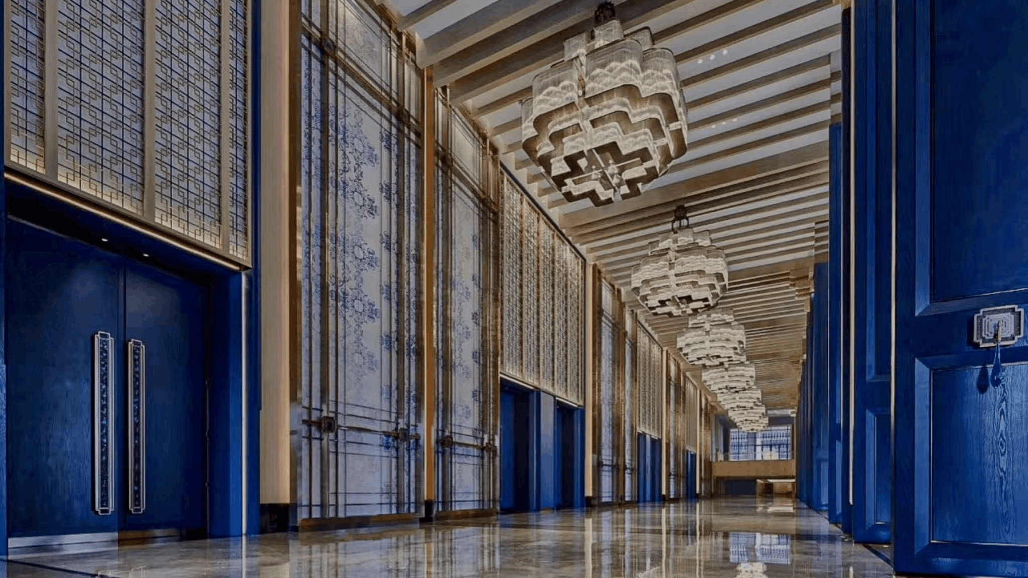 Refined wellness facility lobby with deep blue and gold accents, coffered wooden ceiling, marble walls with circular moon-gate mirror, blue-and-white patterned carpet, lacquered cabinets, and illuminated display shelves creating a tranquil atmosphere