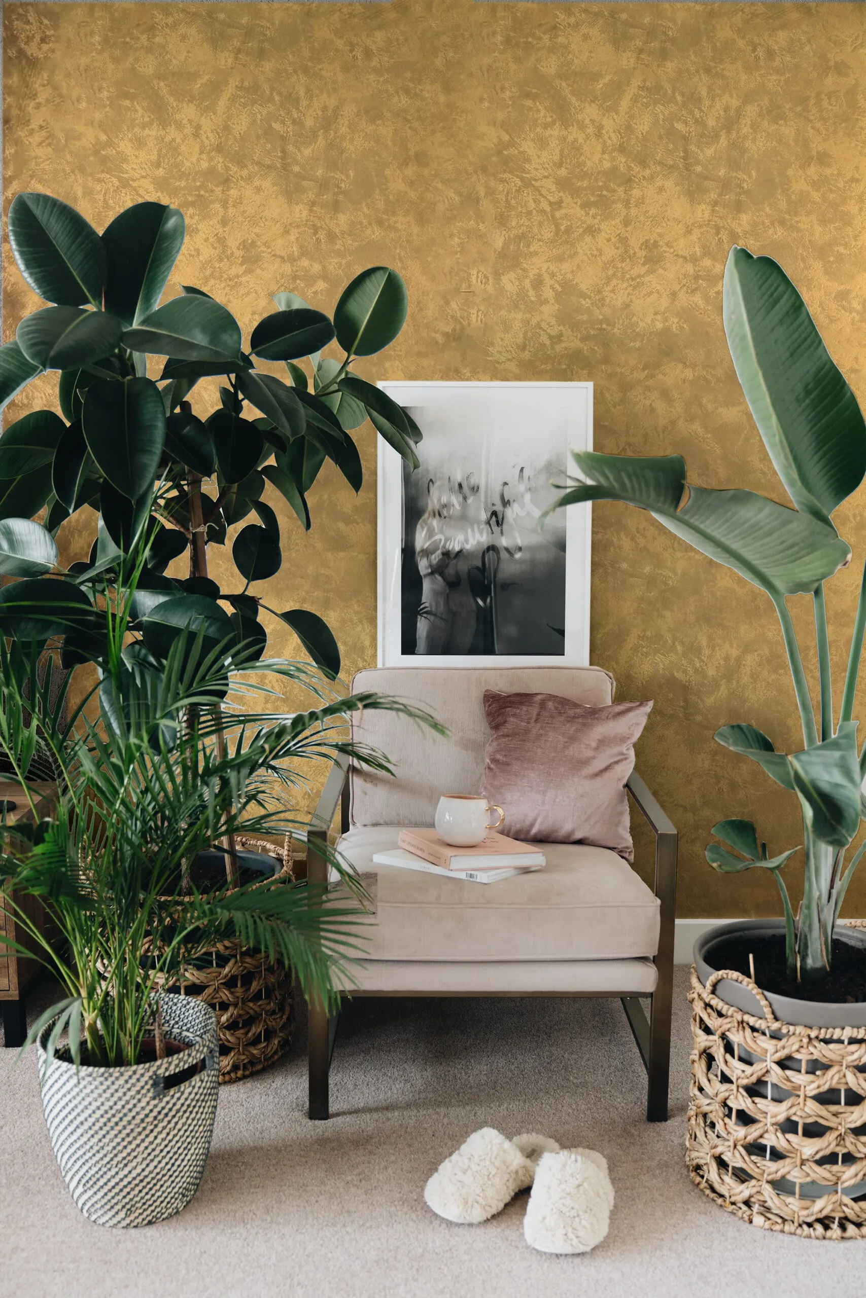 A plush chair with a book and mug sits beside lush plants against a textured gold wall.